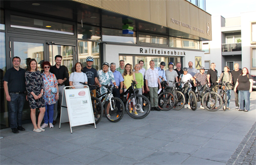 Mitglieder des Gemeinderates, die mit Fahrrädern vor einem Gebäude stehen
